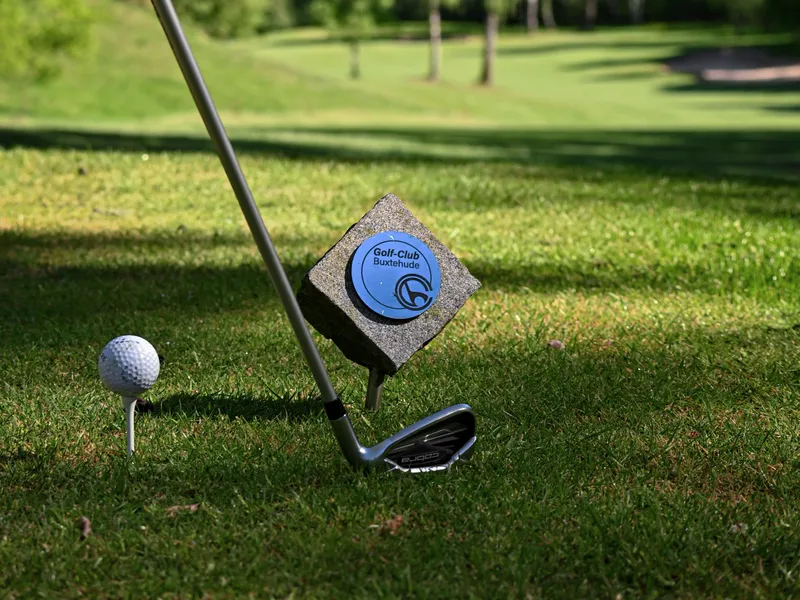 Golfball und Schläger am Abschlag mit Blick auf Fairway und Bunker